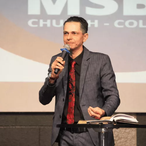 Pr. Leone Passos pregando com uma Bíblia aberta